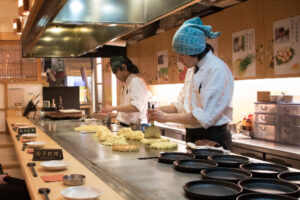 Cooks in Japan making okonomiyaki savory pancake